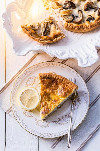 Mushroom champignon pie quiche slice on a ceramic plate on a white wooden background