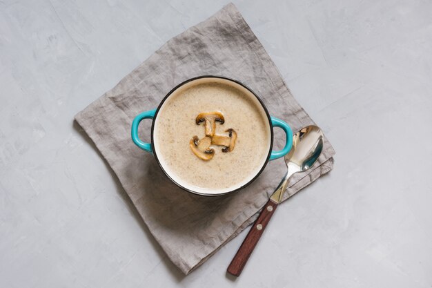 Mushroom champignon soup on grey concrete table. View from above.