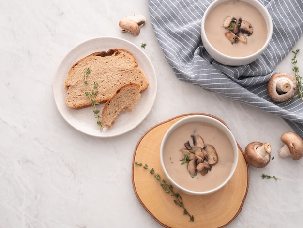 Mushroom cream soup in white bowl with bread on the table. 