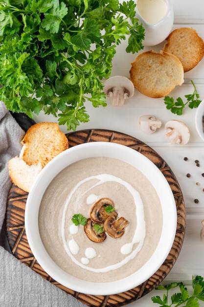 Mushroom cream soup with cream croutons and herb on a white wooden background Delicious comfort food