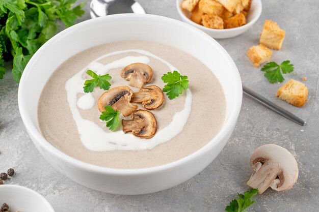 Mushroom cream soup with cream croutons and herbs on a wooden background Delicious comfort food