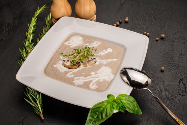 Mushroom cream soup with herbs on wooden background