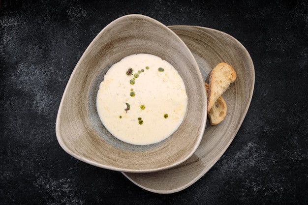 Mushroom cream soup with homemade bread on dark concrete