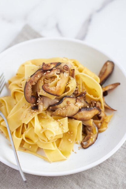 Pappardelle ai funghi e piatto di pasta con shiitake e semi di sesamo