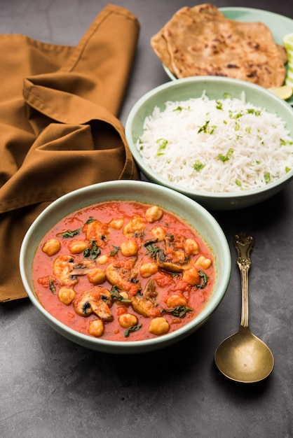 Mushroom sabzi in tomato curry with chickpea and spinach, Indian main course menu served with Paratha and cooked white rice