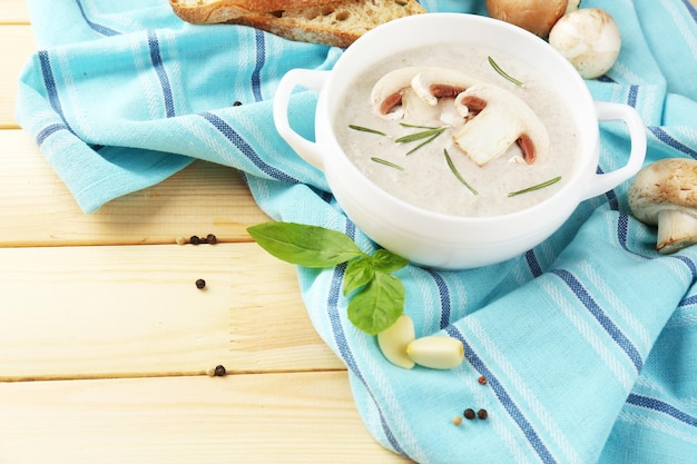 Mushroom soup in pot on napkin on wooden background