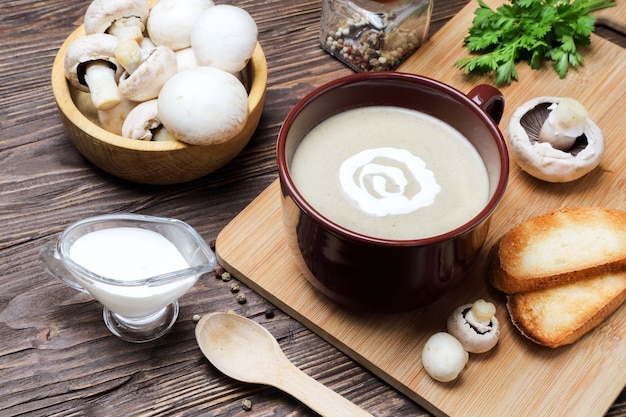 Purea di zuppa di funghi di champignon in una tazza marrone su un tavolo di legno