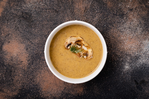 Foto purea di zuppa di funghi in un piatto su un tavolo nero.