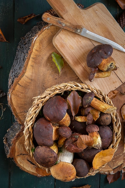 Foto funghi in un cestino su un tagliere con una lama. raccolta di funghi stagionali. preparativi per l'inverno, preparando marinate fatte in casa.