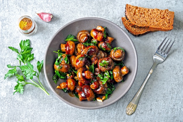 Mushrooms in a bowl, cooked in soy sauce with parsley and garlic. Vegan bowl with mushrooms. Healthy vegan lunch.