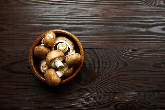 Mushrooms in bowl fresh brown champignons on a wooden table