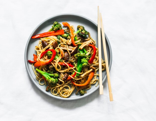 Mushrooms broccoli sweet peppers teriyaki stir fry sauce with noodles on a light background top view