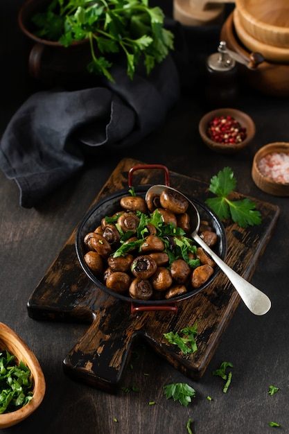 Mushrooms champignon fried in soy sauce, with pepper and steamed onions in an old metal bowl on an old vintage table