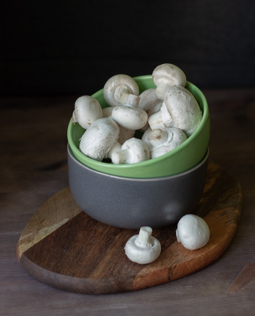 mushrooms champignons in a bowl on a dark