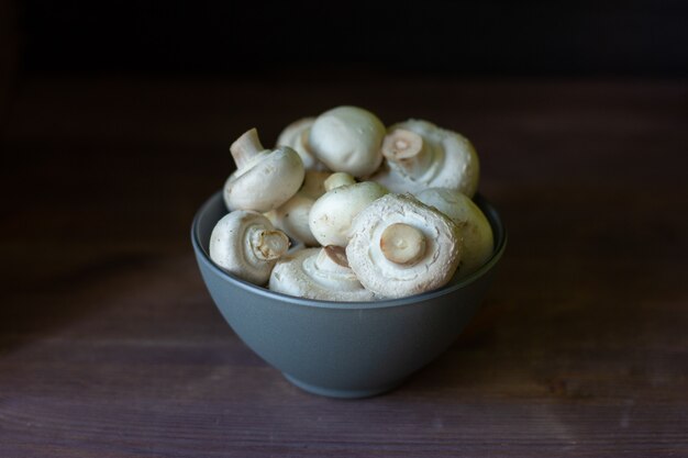 mushrooms champignons in a bowl on a dark