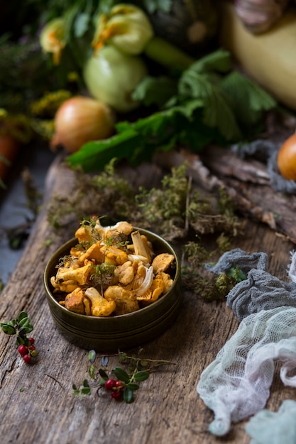 mushrooms chanterelle in a clay plate and vegetables in the background top view 