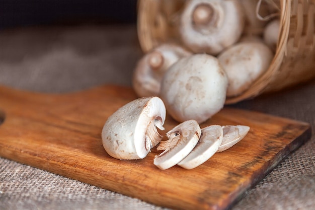 Primo piano affettato dei funghi, trovantesi su un bordo di legno di taglio.