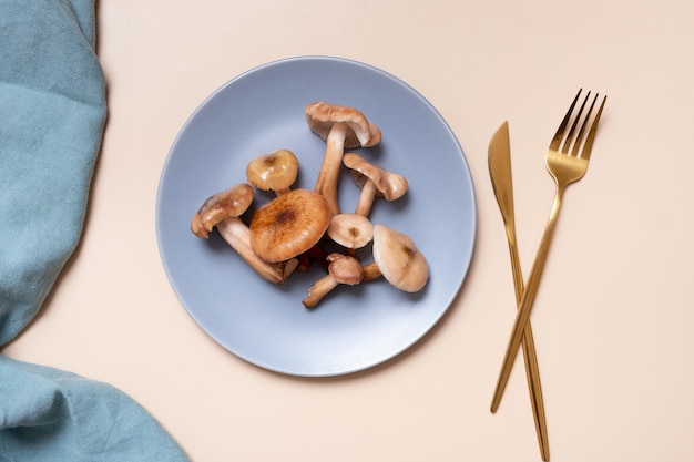 Mushrooms on a plate with cutlery flat lay top view on beige background