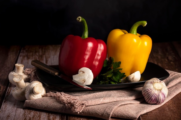 Mushrooms, red and yellow peppers lie on the table in the kitchen