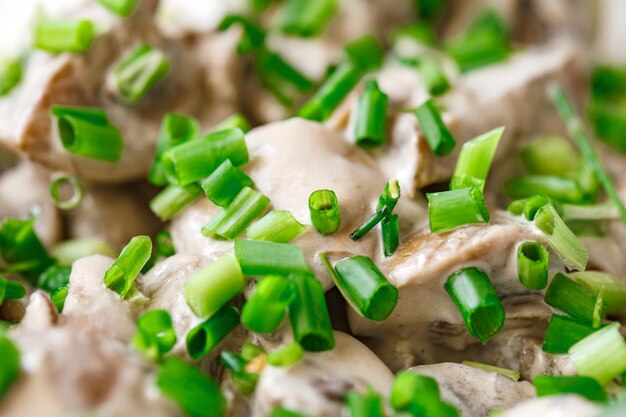 Foto funghi stufati in salsa di crema acida spruzzati di cipolle verdi tagliate close-up selective focus