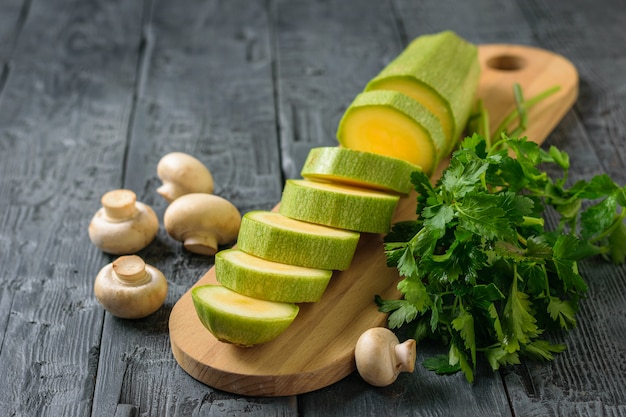 Mushrooms with sliced zucchini and parsley on the black table