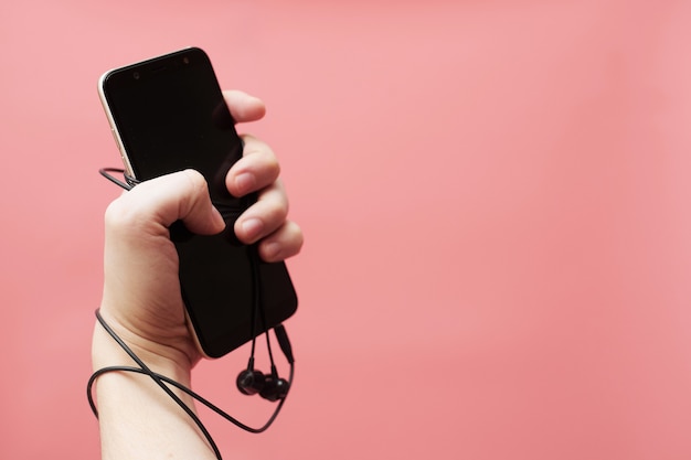 Photo music addiction concept, smartphone tied to hand with wire on pink background. high quality photo