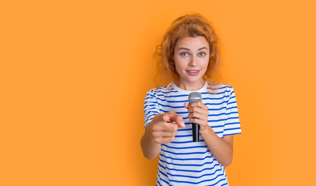 music concept woman singer isolated on yellow background young singer woman sing in music studio woman singer point finger