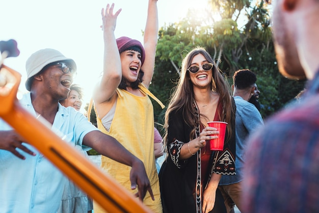 Music drinks and friends dancing outdoor to celebrate at festival concert or summer social event Diversity young men and women people together while excited happy and drinking alcohol at a party