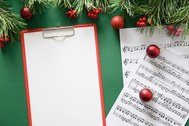 Music empty frame for Christmas Carols and sings decorated red balls on green background