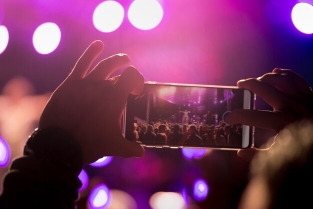 In un festival di musica, un uomo registra il suo concerto sul suo smartphone.