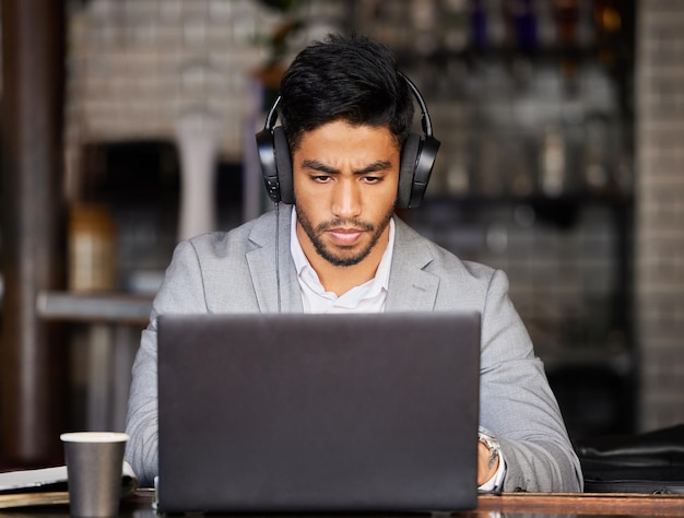 Music gets me in serious business mode Shot of a young businessman wearing headphones while using a laptop at a cafe