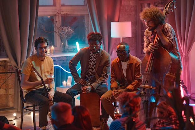 Music group of young men sitting and talking to their fans during performance in the club