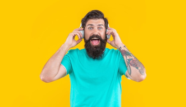Music in headphones of amazed guy dj guy in music headphones isolated on yellow background