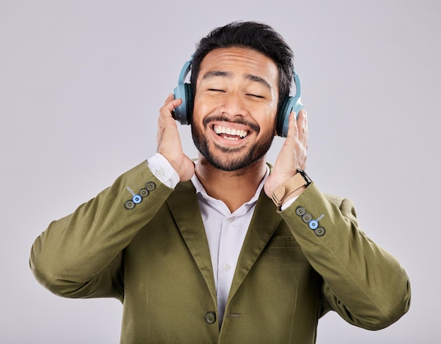 Music headphones and business man singing in studio isolated on a gray background Ceo entrepreneur and smile of happy male singer streaming listening and enjoying podcast radio and song album