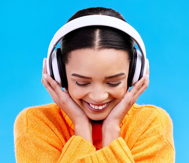 Music headphones woman and smile on blue background studio and color backdrop Happy female model listening to sound streaming album and audio connection on media gen z and hearing radio podcast