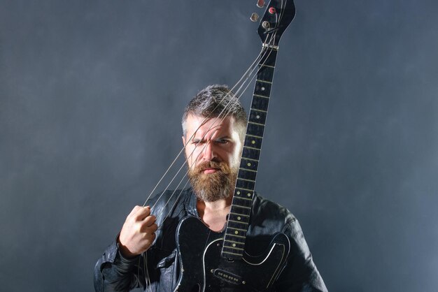 Music hobby guitar player in jacket with electric guitar rock or punk music concert bearded man with