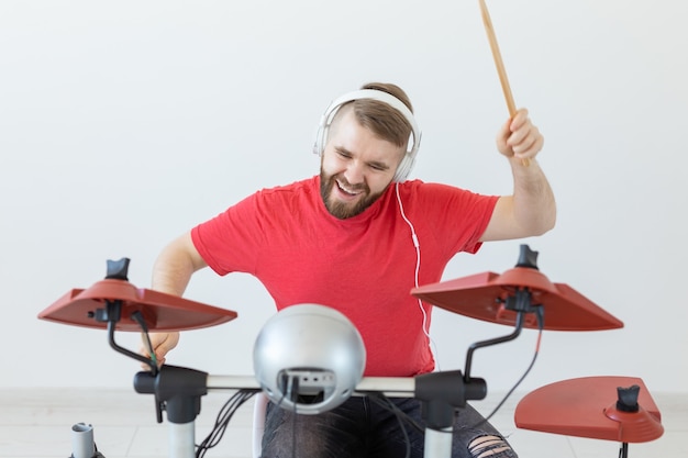 Musica, hobby e concetto della gente - batterista del giovane che gioca i tamburi elettronici.