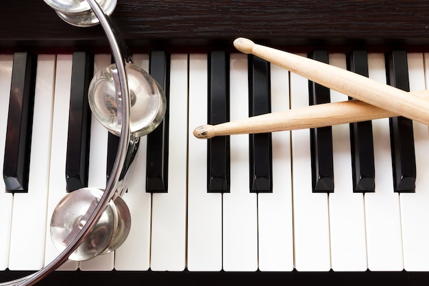 Music instruments. Drum sticks and tambourine on piano. 