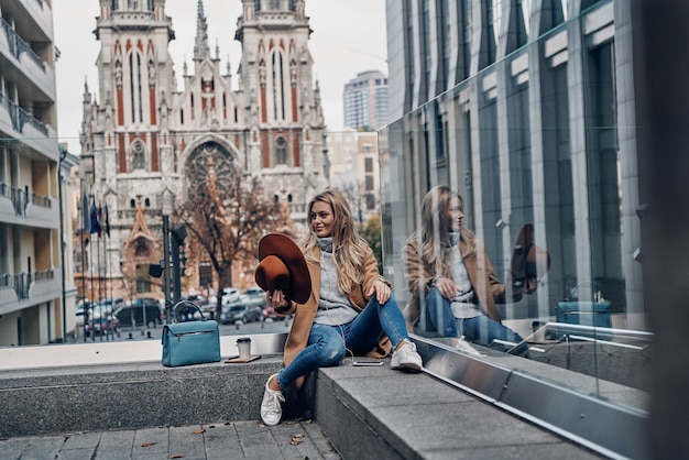 Music is her life. Attractive young woman listening music using her smart phone while spending carefree time in the city