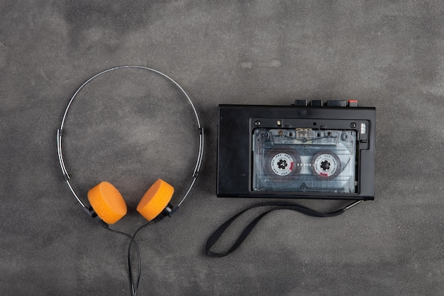 Music listening concept Vintage cassette tape audio player and headphones closeup on grey concrete background top view