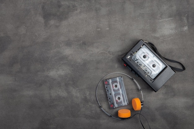 Music listening concept Vintage cassette tape audio player and headphones closeup on grey concrete background top view