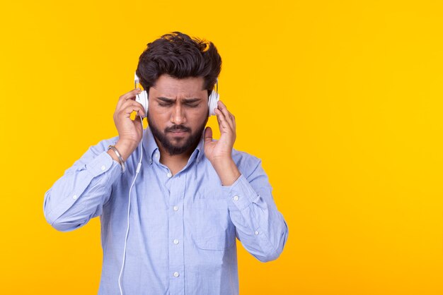 Music, meloman and people concept - A happy indian man listening to music and enjoying it over