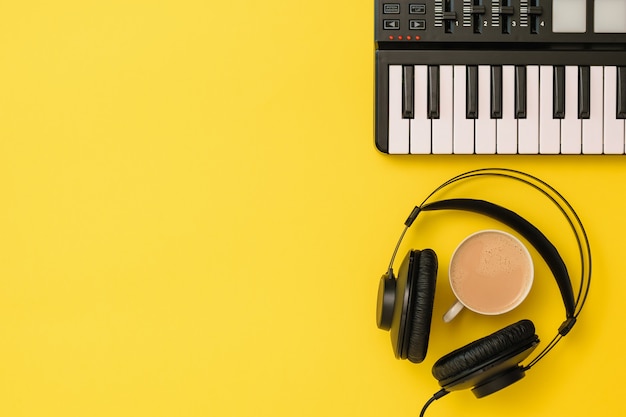 Music mixer and black headphones and coffee on yellow background. Equipment for recording music tracks. The view from the top. Flat lay.