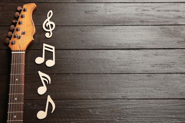 Музыкальные ноты и гитарная шея на деревянном фоне сверху Пространство для текста