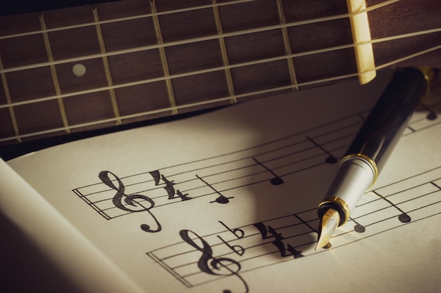 Music notes and old book on wooden table