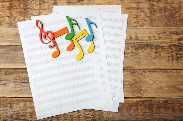 Music notes and sheets of paper on wooden background