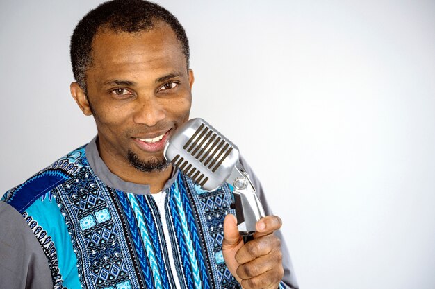 Music performer singing a song with a vintage silver microphone. ethnic afro man performing old music industry