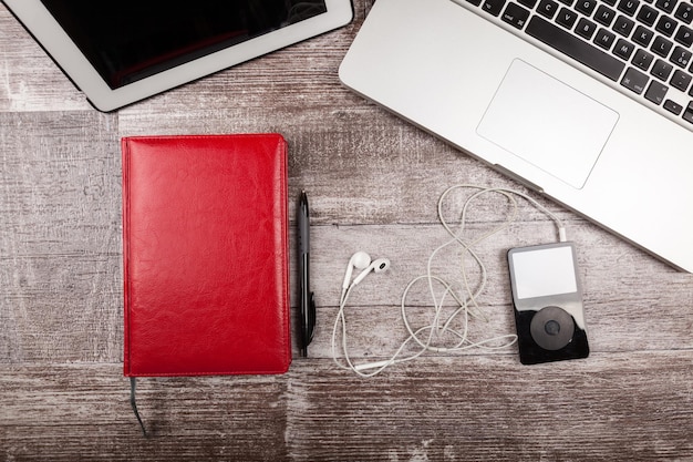 Music player, laptop and writing notebook from above view on a wooden background