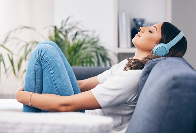 Music relax and quiet with a woman in her home listening to the radio while sitting on the living room sofa Peace wellness or headphones with an attractive young female streaming audio in a house