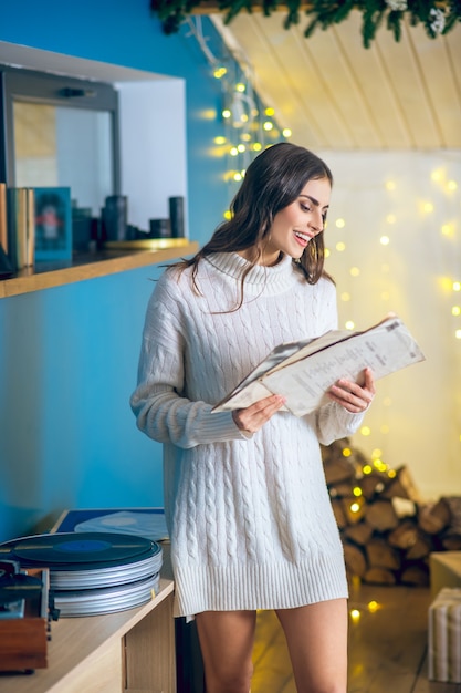 Music for relaxation. Cute woman in white clothes holding a record in her hands